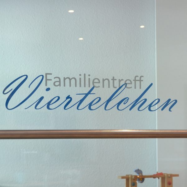 Text auf Glasfenster: "Familientreff Viertelchen" in blauer Schrift.