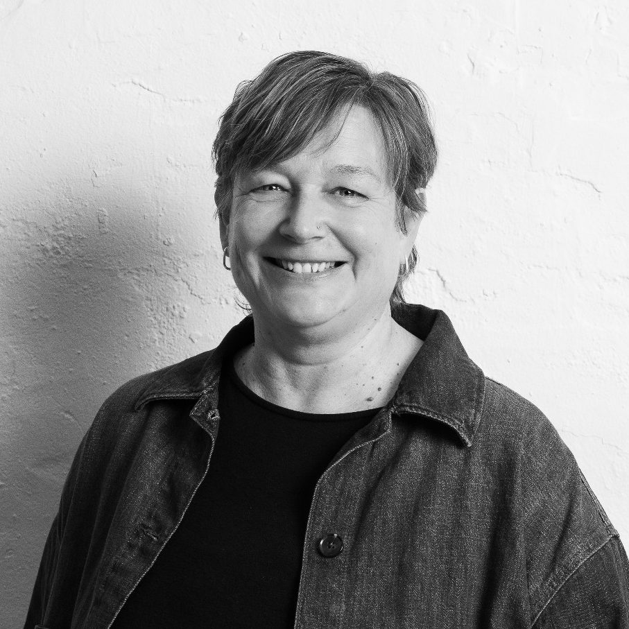 Miriam Schulz lächelnd mit kurzen Haaren vor einer hellen Wand.