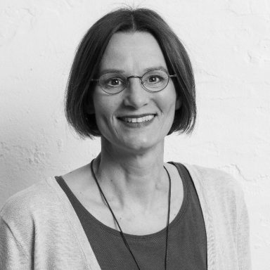 Christiane Brinkmann mit kurzen Haaren und Brille, lächelt freundlich, trägt einen hellen Pullover.
