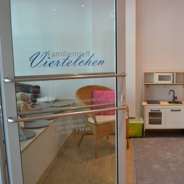 Bunter Kasten mit Wachsmalkreiden, im Hintergrund zeichnet ein Kind.