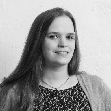 Leonie Lange mit langen, glatten Haaren und einem lächelnden Gesicht vor hellem Hintergrund.