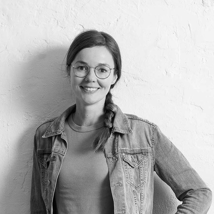 Lisa Bokeloh Lisa Bokeloh mit Brille, die in einem hellen Raum steht und verschränkte Arme hat.