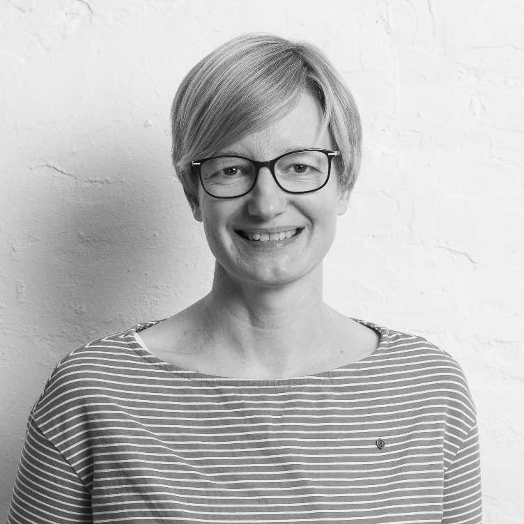Sandra Weggebakker Sandra Weggebakker lächelnd mit Brille in gestreiftem Shirt vor hellem Hintergrund.