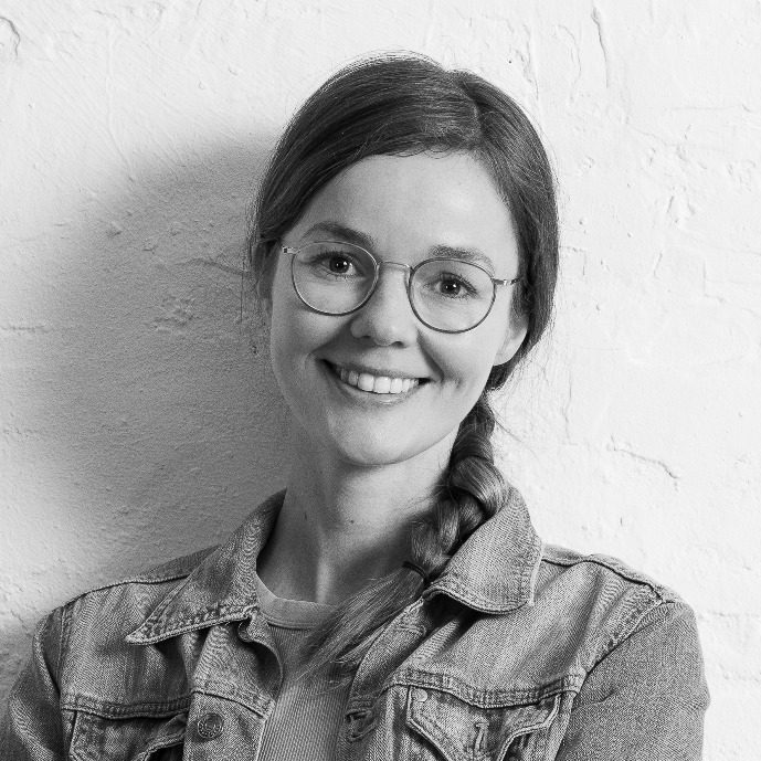 Lisa Bokeloh mit Brille, die in einem hellen Raum steht und verschränkte Arme hat.