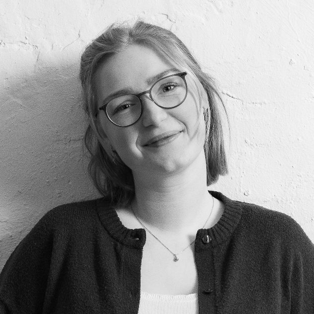 Sophie Berger Sophie Berger mit Brille und kurzer Frisur, lächelt vor einer hellen Wand.