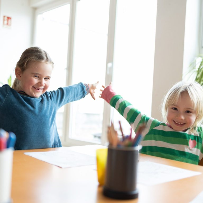 Ein kleines Mädchen sitzt auf den Schultern eines Erwachsenen und formt mit den Händen ein Fernrohr.