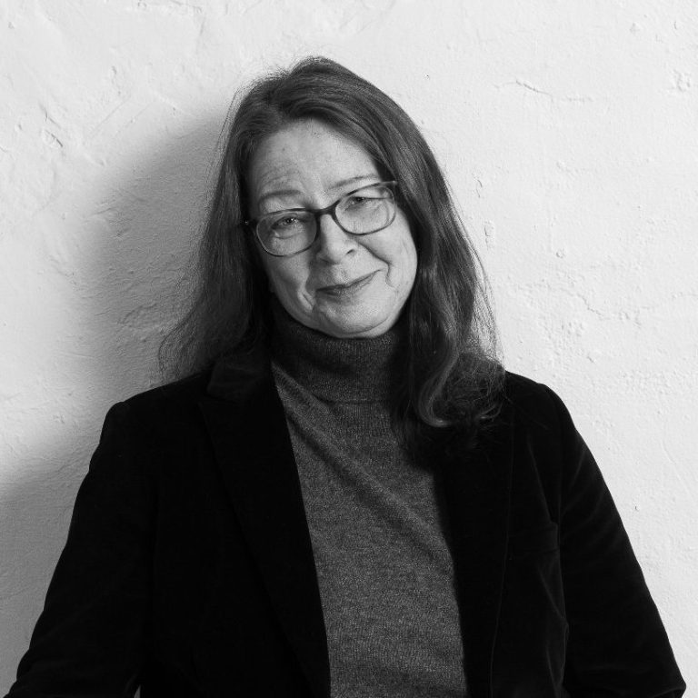 Celine Stenner-Petrat Schulsozialarbeiterin Schwarz-Weiß-Foto von Celine Stenner-Petrat, Schulsozialarbeiterin lächelnd, vor einer hellen Wand.